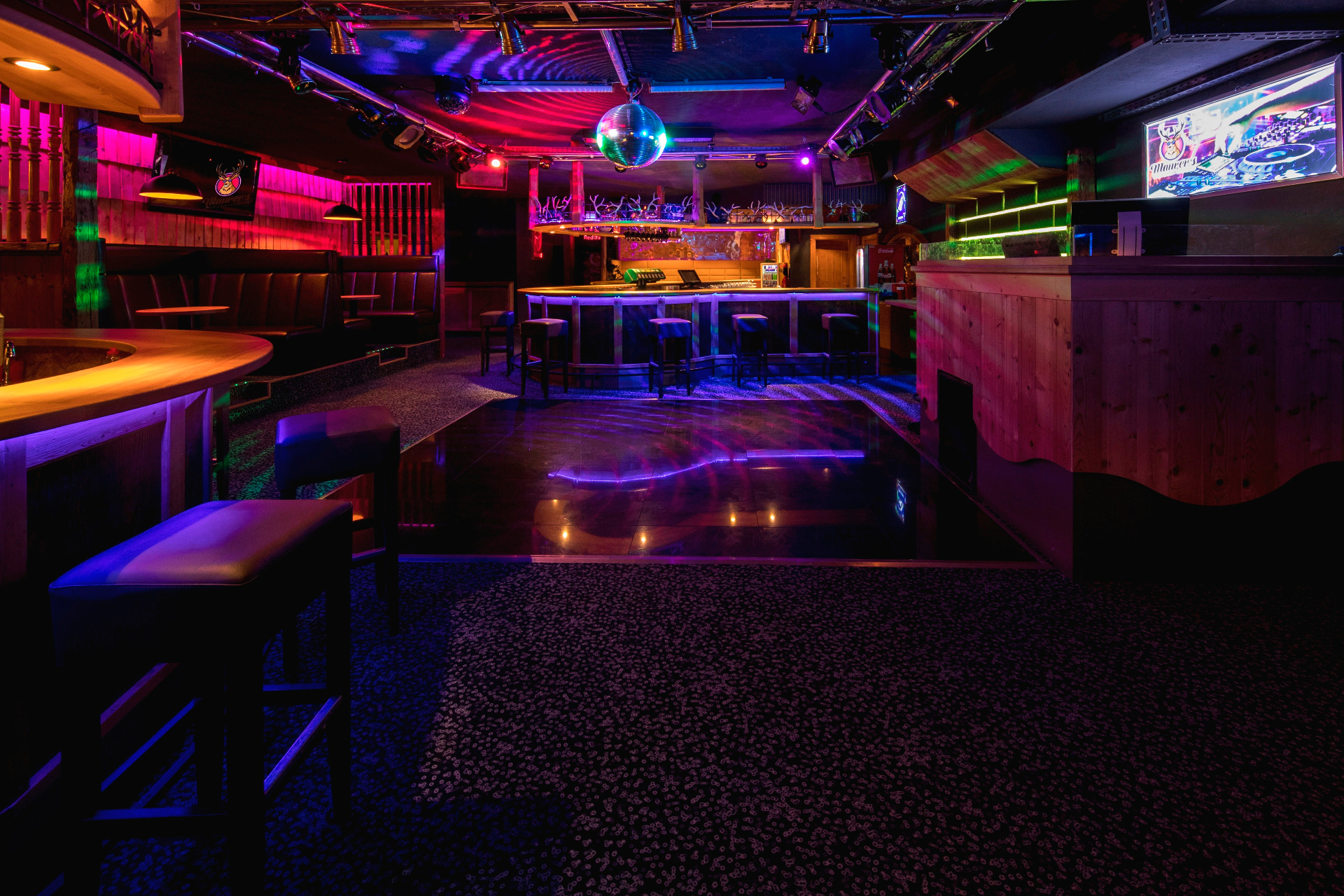 Innenansicht des Maurer's Disco mit beleuchteter Tanzfläche, Bar und Spiegelkugel
